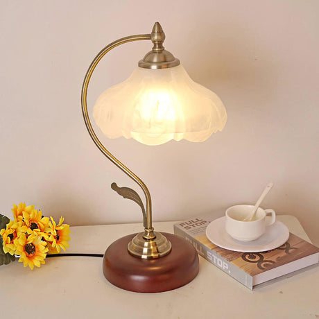 Flower shade lamp lit beside sunflowers, a cup and stacked books