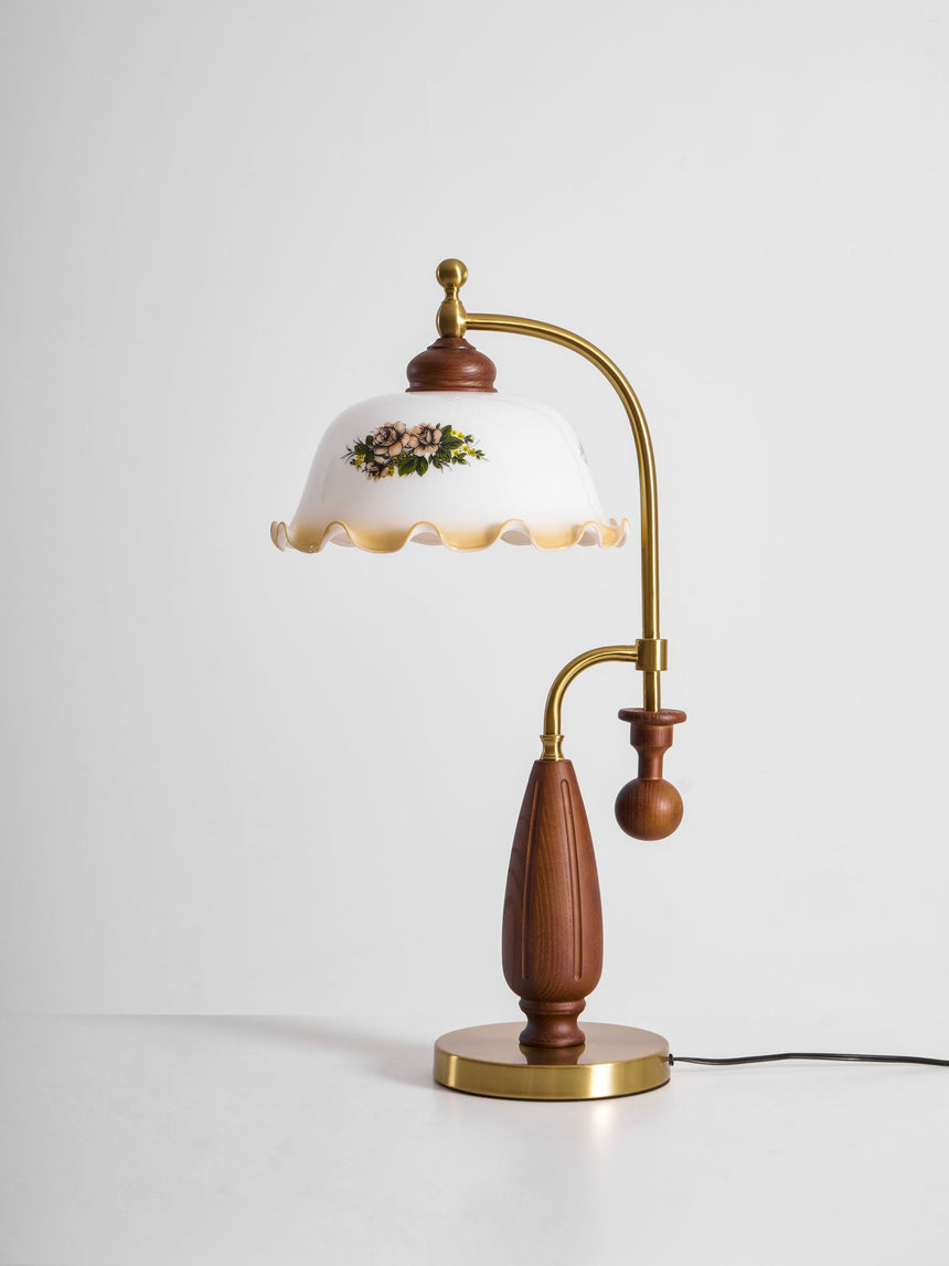 Antique brass table lamp seen from the front on a plain ground