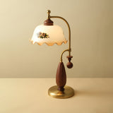 Antique brass table lamp lit against a plain warm ground