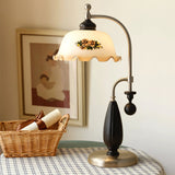 Antique brass table lamp lit on a checked cloth beside a basket