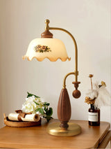 Antique brass table lamp lit on a table beside white flowers