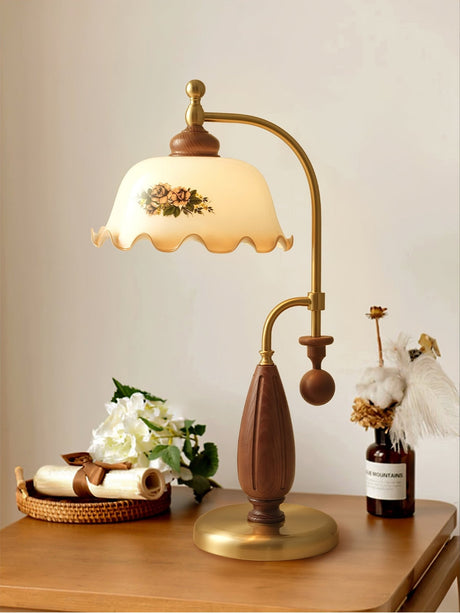Antique brass table lamp lit on a table beside white flowers