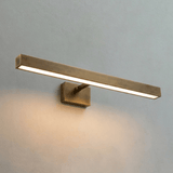 The longest brass bar lit on a pale wall, light running the length of its face