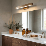 Brass bar lit along a long mirror over a stone counter with jars and a plant