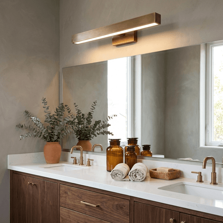 Brass bar lit along a long mirror over a stone counter with jars and a plant