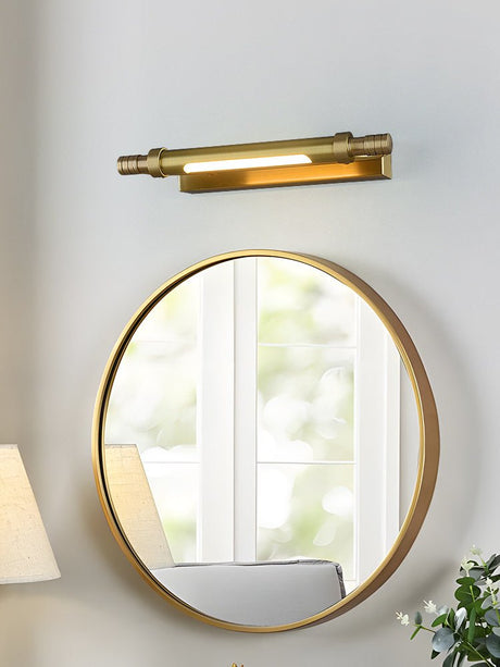Brass tube lit above a round gold mirror on a pale painted wall