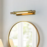 Brass tube lit above a round gold mirror reflecting a bright window
