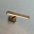 The shortest brass bar lit on a pale wall, the block bracket under its middle