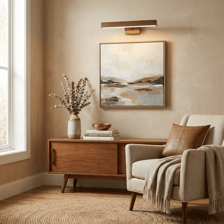 Brass bar lit above a framed canvas on a walnut sideboard beside an armchair