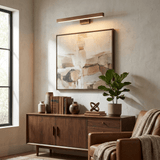 Brass bar lit above a framed canvas over a walnut sideboard beside a chair