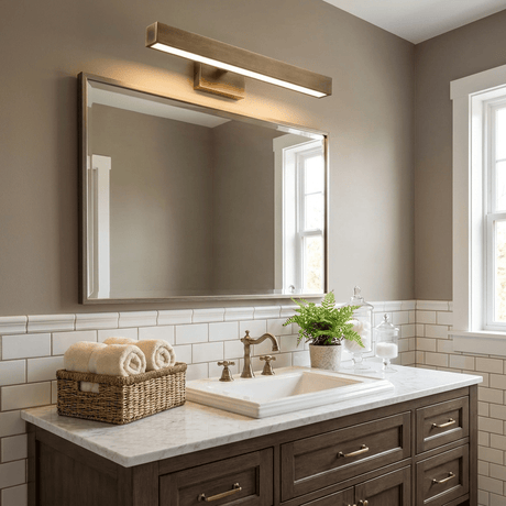 Brass bar lit above a wide mirror over a double basin vanity on a tiled wall