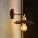 The brass arm and round walnut backplate seen against a dark wall