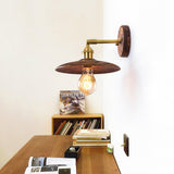 Sconce lit above a low bookcase stacked with books and magazines