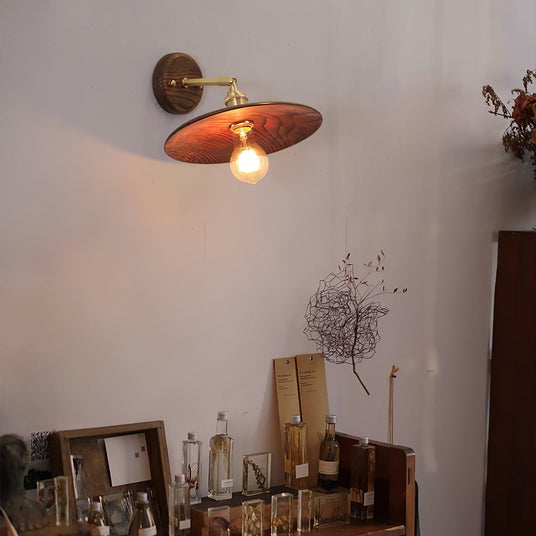 Sconce lit above a shelf of books and small objects in a living room