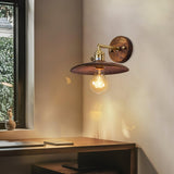 Brass and walnut sconce lit on the wall above a wood work table