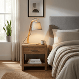 Arc lamp lit on a wood nightstand beside a bed and a plant