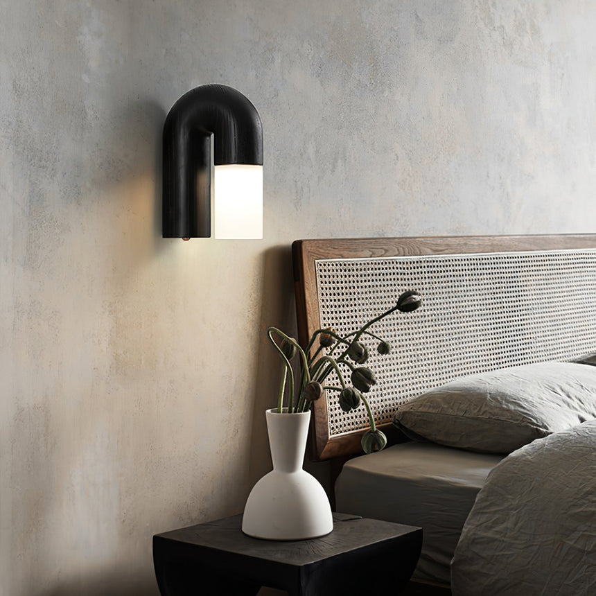 Black arch lit above a bed beside a nightstand holding a stone vase