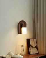 Sconce lit above a console with a shell, a frame and a curtain beside it