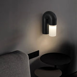 Black arch lit on a dark wall above a sofa and a low round side table