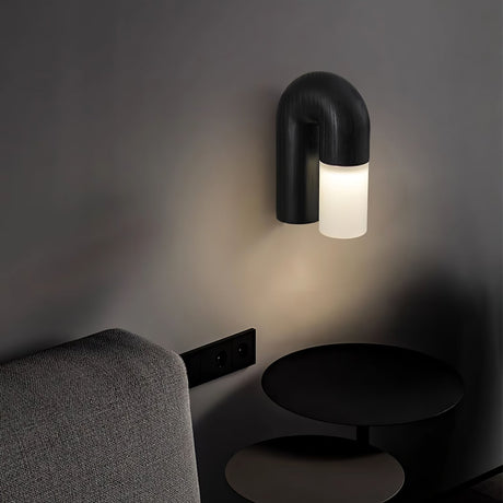 Black arch lit on a dark wall above a sofa and a low round side table