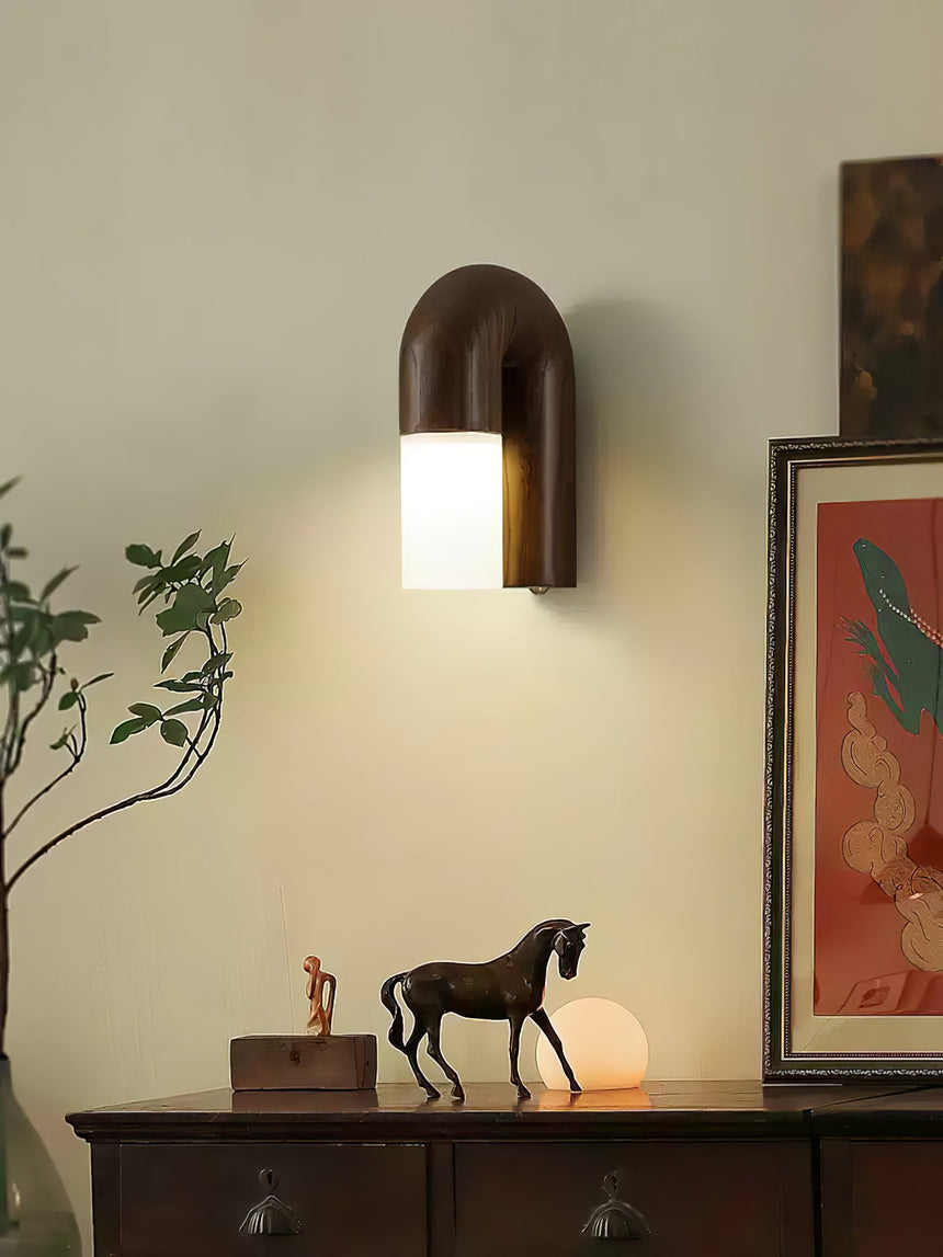 Sconce lit in an entry above a console with a horse figurine and a print