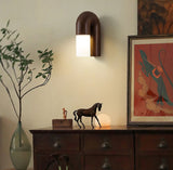 Sconce lit above a sideboard with a vase of branches and framed prints