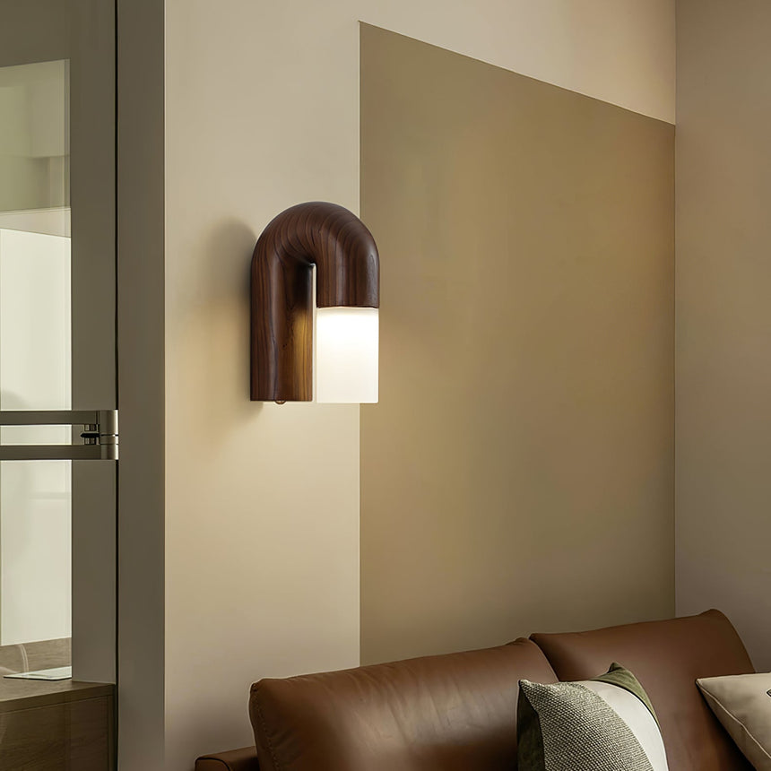 Sconce lit on a beige wall above a leather sofa beside an open doorway