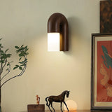 Sconce lit beside framed artwork above a horse figurine and a plant