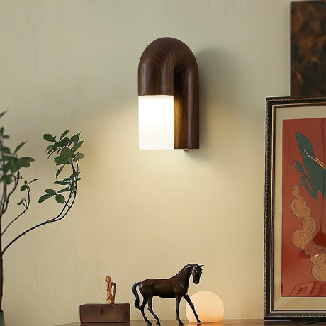Sconce lit beside framed artwork above a horse figurine and a plant