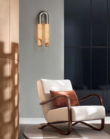 The sconce lit above a white armchair beside a dark paneled wall