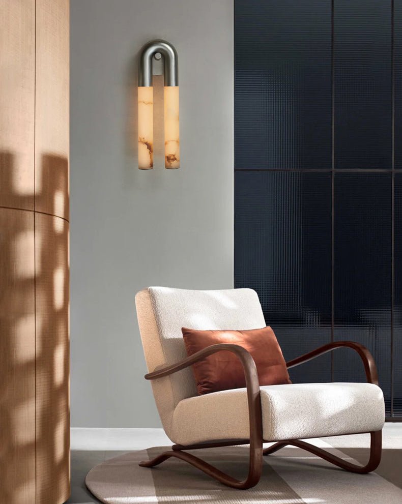 The sconce lit above a white armchair beside a dark paneled wall
