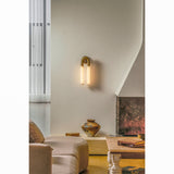 The sconce on a white wall above a low sofa and a large urn