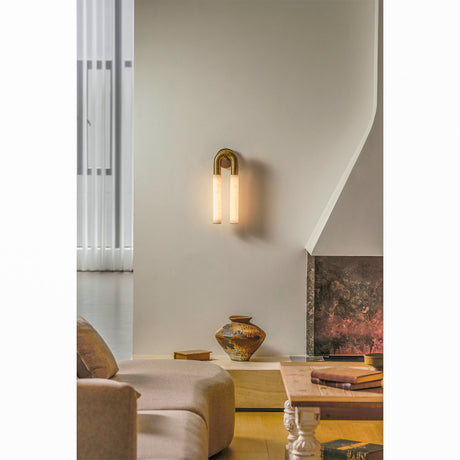 The sconce on a white wall above a low sofa and a large urn