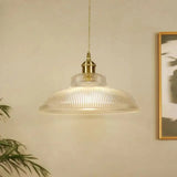 Clear prismatic shade hanging in front of a framed print on a pale wall