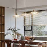 Three amber shades in a row above a long dining table beside a window