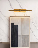 Brass twin bar lit over framed artworks leaning against a marble wall