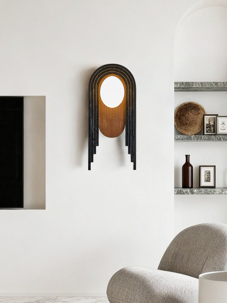 The lamp on a living room wall between a fireplace opening and shelves