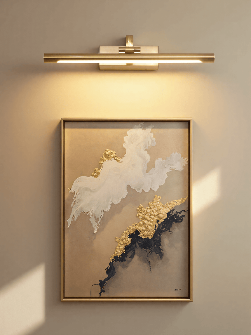 The gold bar lit over a framed abstract canvas in blue and gold on a warm wall