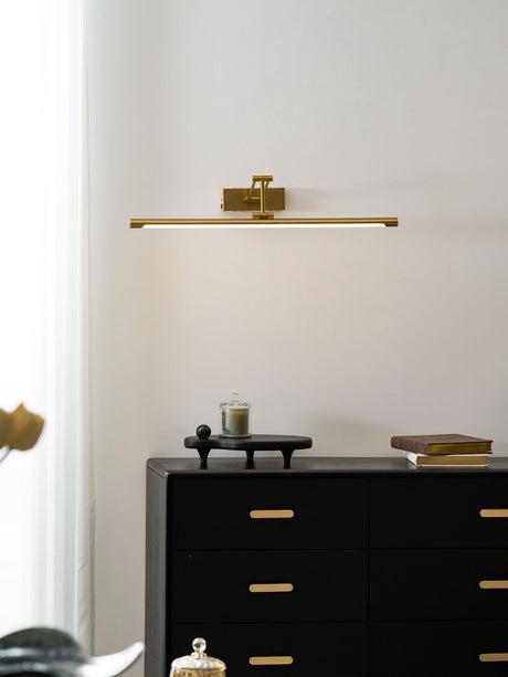 Lit above a black chest of drawers holding books and a small brass sculpture