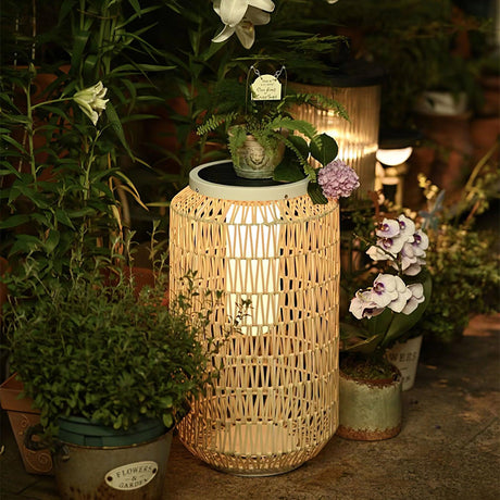 The tall lantern lit on a terrace beside pots of flowers and planting