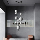 Several sphere pendants lit above a dark dining table with figures artwork