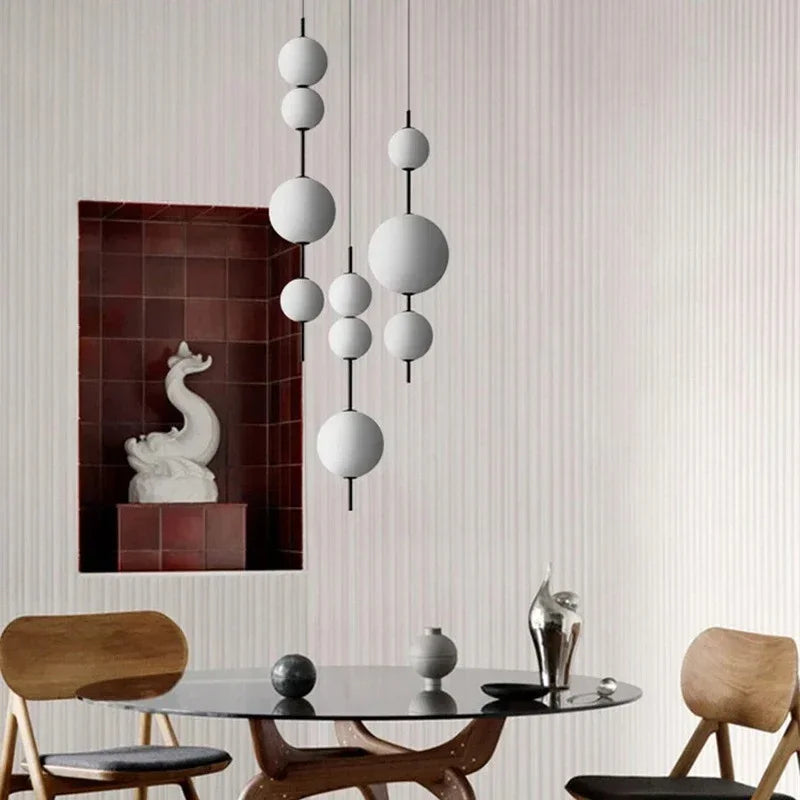 Two sphere pendants above a round dining table with pale wooden chairs