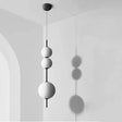 Three white spheres threaded on a black rod against a pale plaster wall