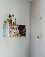 The ball light below a marble shelf with a plant