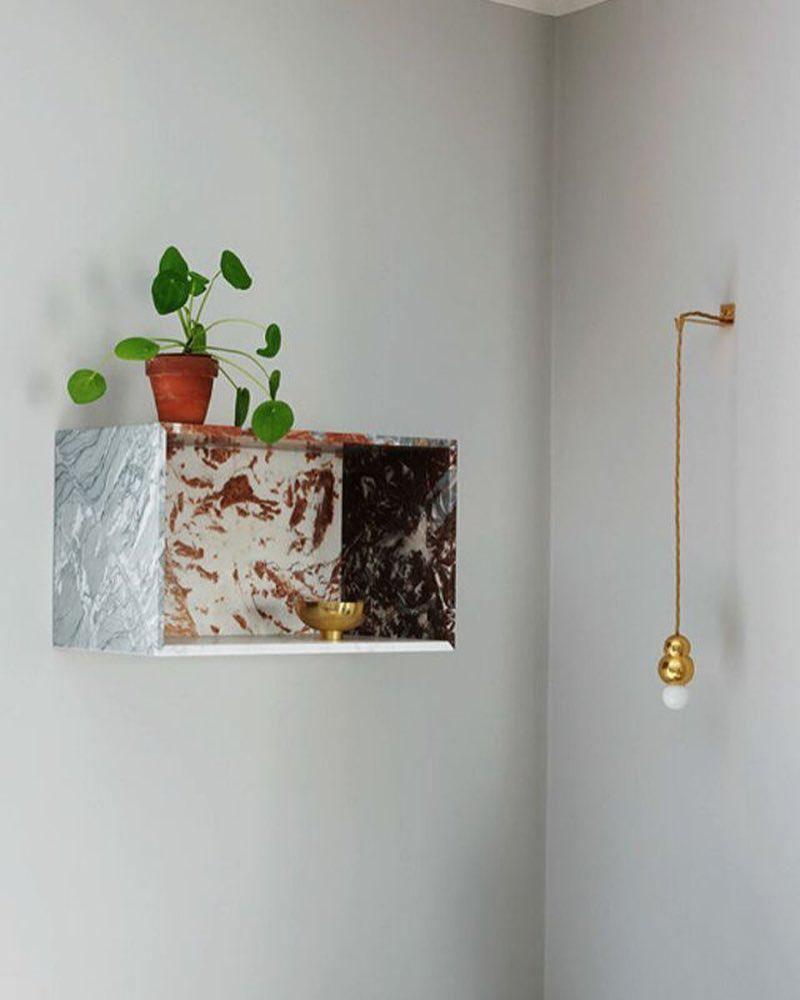 The ball light below a marble shelf with a plant