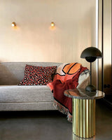 Two ball lights lit above a gray sofa beside a gold side table
