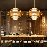 A row of tiered bamboo shades lit above wood dining tables and cane chairs
