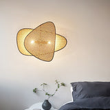 The cane sconce lit above a bed with dark linens and a small side table