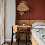The cane sconce on a terracotta wall above a small desk and a bed