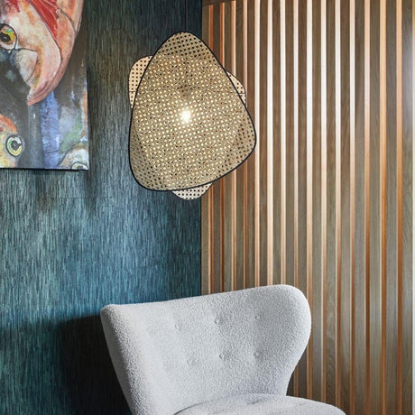The cane sconce on a dark wall above a white wool chair beside wood slats